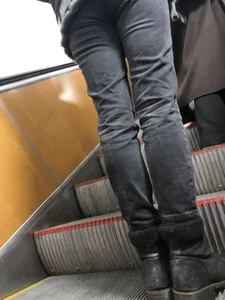 Legs in tight jeans closeup on subway escalator