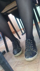 College teen's legs in black pantyhose and feet i ngrubby shoes closeup in class