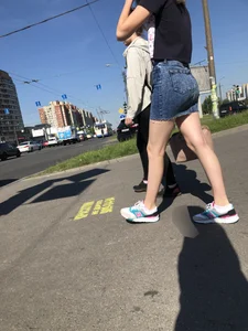 Cute Girl in a Short Denim Skirt Walking on a Street And Waiting on a Crosswalk Gallery