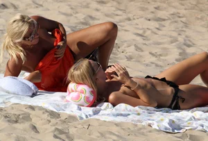 Topless mom and daughter on the beach getting some sun