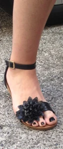 Feet in sandals with toenails painted black closeups