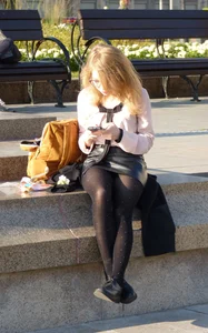 Cute Girl in Leather Skirt and Black Pantyhose Sitting on the Pavement
