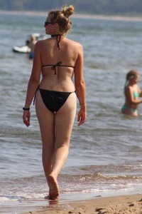Strawberry blonde sexy mature girl walking the beach in black bikini