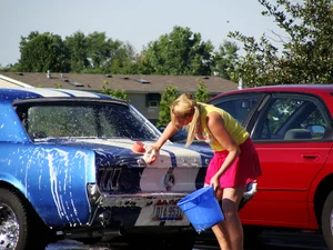 Group of cute girls at a car wash in bikinis and shorts