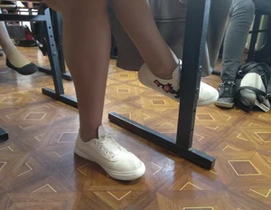 Crossed Legs in Pantyhose and Feet in Sneakers of a Colleege Teen in a Classroom Photo