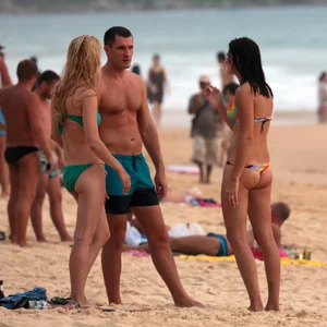 Sexy brunette in thong bikini and blonde friend in green bikini at the beach