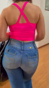 Giant sexy butt in denim jeans, hot girl weating a pink top planning to hand a watch on the wall
