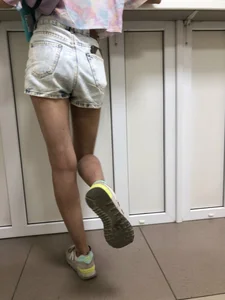 Girl in Denim Shorts With Very Skim Hot Legs And Worn Sneakers at the Reception Desk