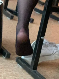 College teen's feet in black pantyhose, closeups in class