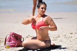 Huge boobed thick brunette babe on the beach in a bikini