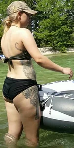 Tattooed girl in a swimsuit getting into an inflatable boat