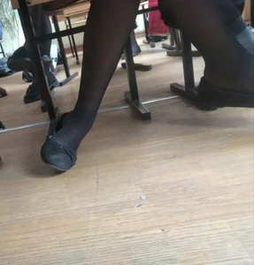Skinny Leg and Foot of a Female Student in Black Pantyhose and Flats Under Desk in a Classroom Photo