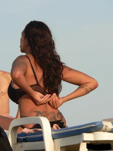 Topless tattooed lady on the beach with fake big tits