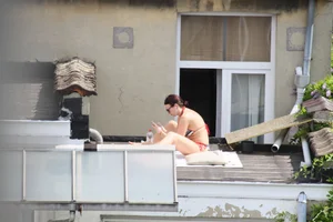 Neighbor on rooftop tanning in bikinis
