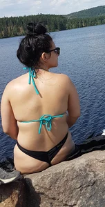 Thick brunette at the lake in a black thong bikini