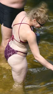 Chunky blonde enjoying some drinks in the water in her purple bikini