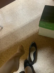 College girl's feet in pantyhose with flats taken off under desk photo