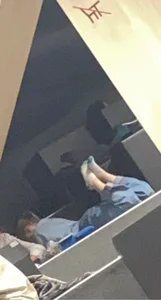 Cute Teen in Loose Jeans And Socks Lying on Her Stomach on Top of Desk