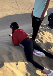 A Candid Teen Girl in Tights Lying on Her Tummy on the Sand-surfing Board