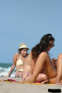 2 topless girls at the beach in thongs