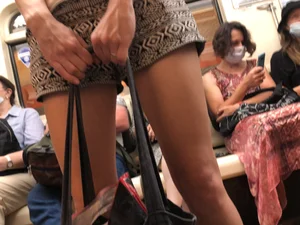 Candid Girl's Spread Legs in Shorts And Hands Holding a Bag Closeup in a Subway Train