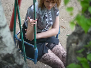 Young Candid Girl in a Skirt And Stockings Sitting on a Swing