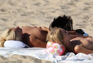 Topless mom and daughter on the beach getting some sun
