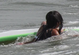 Brunette bikini girl on the beach and surfing in her bikini