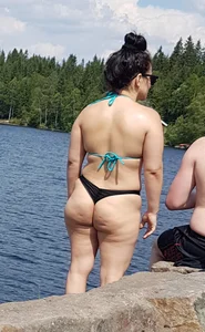 Thick brunette at the lake in a black thong bikini