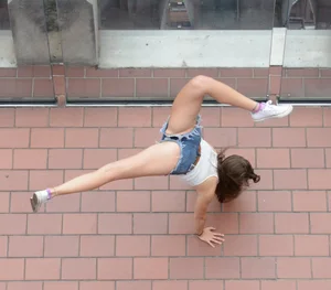 Girl trying to do a handstand in fringed mini shorts