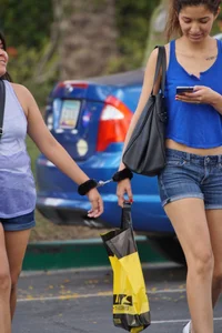 Sexy girl in denim shorts handcuffed to her friend outside