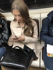 Cute girl with skinny legs in black pantyhose sitting in a subway train