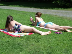 Two hot girls in swimsuits with very pale skin lying on the grass in a park