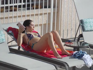 Sexy ass brunette sunbathing by the pool in thong bikini