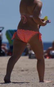 Thick blonde girl in an orange bikini on the beach