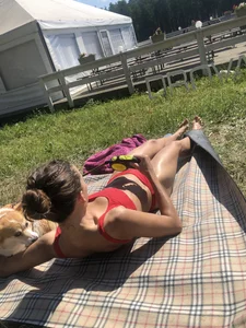 Gorgeous Skinny And Fit Girl in Red Swimsuit Lying on the Grass With a Cute Corgi