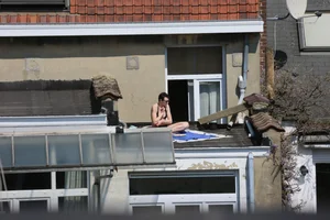 Neighbor on rooftop tanning in bikinis