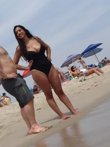 Thick brunette with huge boobs on the beach in black swimsuit