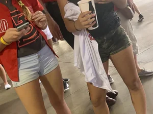 Bunch of girls in various outfits at a Cardinals baseball game