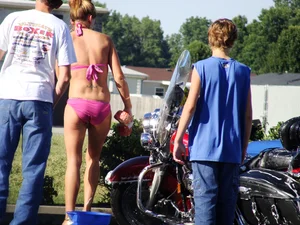 Group of cute girls at a car wash in bikinis and shorts