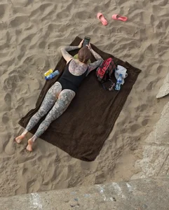 Chubby Girl in Body Swimsuit Covered With Tattoos Lying on the Beach