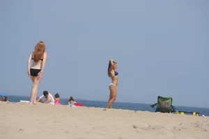 Redhead and brunette friends looking sexy in bikinis on the beach