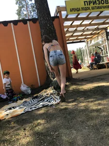 Young Skinny Girl Taking Off Her Denim Shorts Leaving a Swimsuit - Bending Over While Laying a Blanket on the Ground at a Lake Nature Park Gallery
