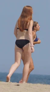 Redhead and brunette friends looking sexy in bikinis on the beach