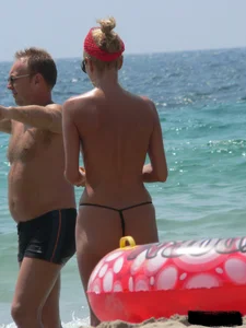 Topless skinny blonde lady in a g-string bikini at the beach