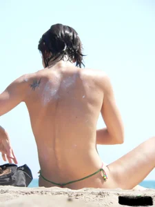 Topless beach milf looking sexy in a tiny g-string bikini