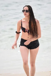 Brunette girl in black shorts and bikini top on the beach