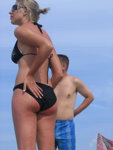 Cute blonde on the beach in a black bikini with nice boobs
