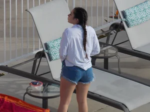 Sexy ass brunette sunbathing by the pool in thong bikini