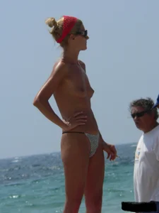 Topless skinny blonde lady in a g-string bikini at the beach